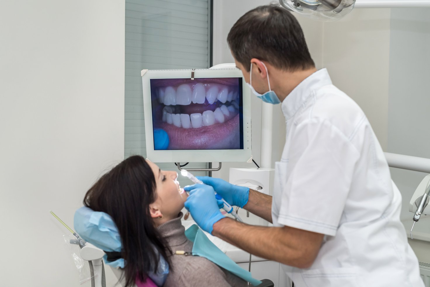 Dentist examining patient's teeth with intraoral camera